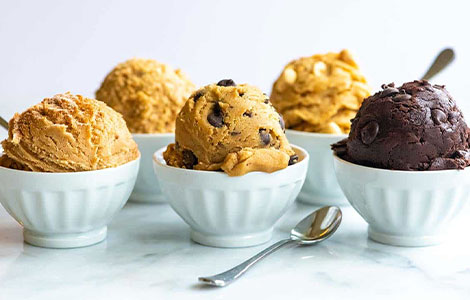 Colorful fruit smoothies in glass jars with fresh kiwi, berries, and 
strawberries on a wooden table at Cream Curls Dunfermline 
